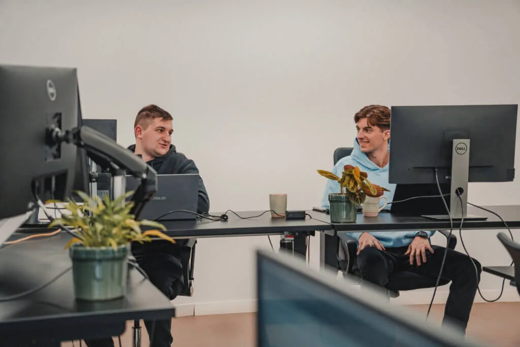 people sitting in an office in front of a computer screen looking at each other